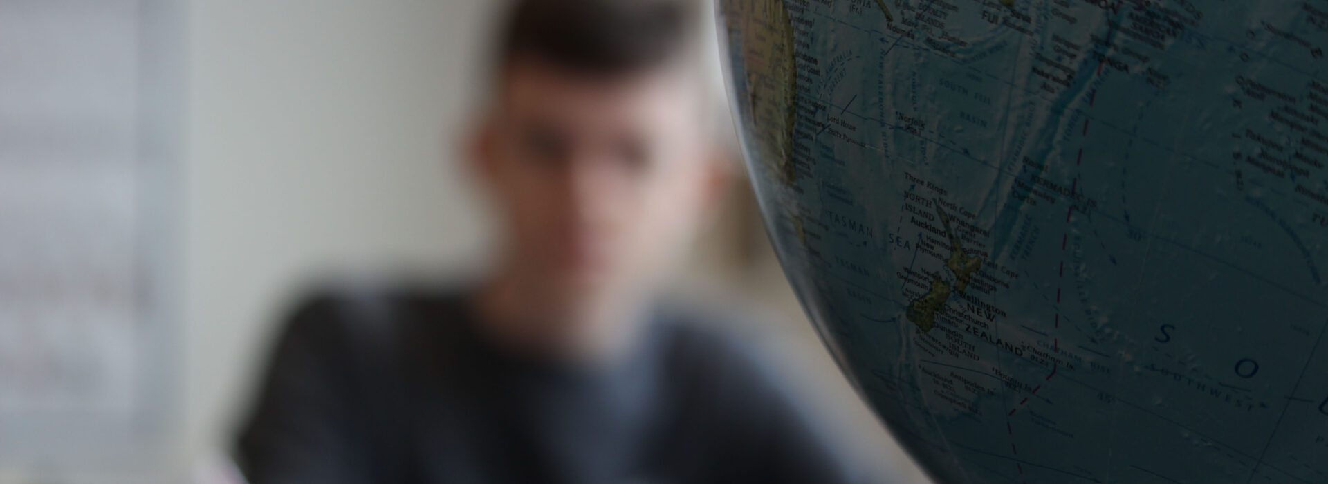 Photograph of a student studying Geography next to a globe